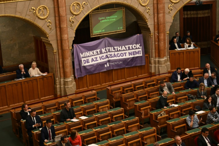 Des élus déploient une banderole au Parlement hongrois pour protester contre le vote d'un amendement constitutionnel ciblant les LGBT+ et les binationaux, le 14 avril 2025 à Budapest ( AFP / Attila KISBENEDEK )