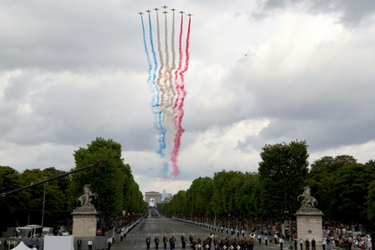 L'équipe d'élite de voltige aérienne de l'Armée de l'air française, la "Patrouille de France" (PAF), libère des traînées aux couleurs nationales de la France alors qu'elle effectue un survol lors du défilé militaire annuel de la Fête nationale, sur l'Avenue des Champs-Élysées avec l'Arc de Triomphe en arrière-plan, à Paris, le 14 juillet 2025 ( AFP / Ludovic MARIN )