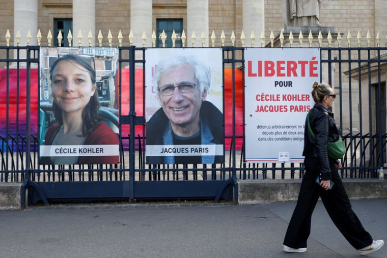 Une femme passe devant des affiches avec les portraits de Cécile Kohler et Jacques Paris à Paris