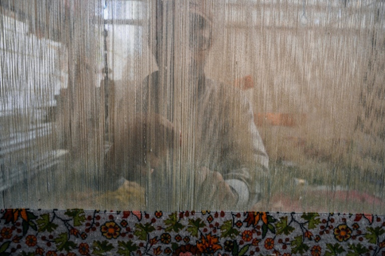 Un artisan cachemiri tisse un tapis en soie dans une usine à Srinagar, le 5 octobre 2021 ( AFP / Tauseef MUSTAFA )