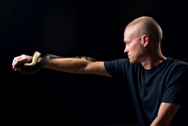 Photo non datée obtenue auprès de Centivax, le 30 mai 2025, de l'Américain Tim Friede, qui s'est exposé au venin de serpent des centaines de fois dans le but de renforcer son immunité, avec un cobra d'eau sur son bras ( CENTIVAX / - )