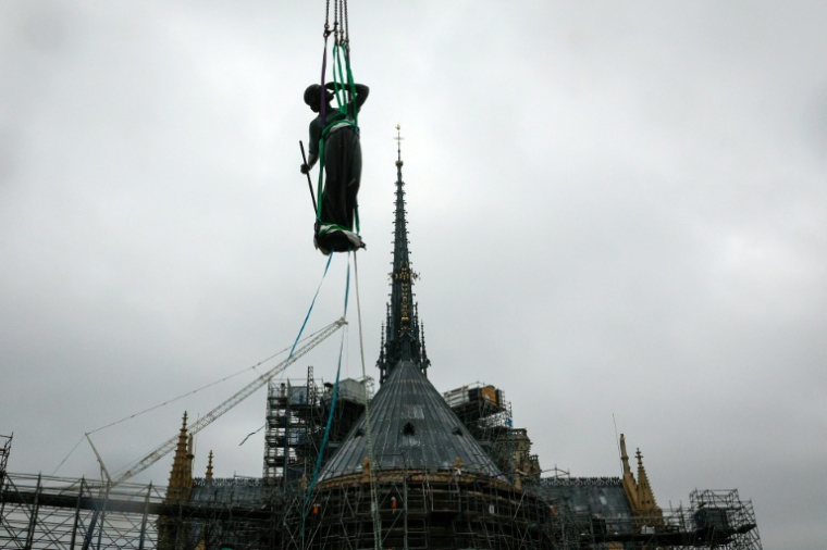 Une grue soulève une statue de Saint-Thomas pour la placer sur la flèche de Notre-Dame de Paris, le 24 juillet 2025 ( AFP / GEOFFROY VAN DER HASSELT )