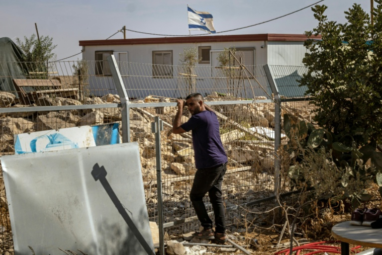 Un Palestinien pose devant une installation israélienne derrière une clôture, dans son village d'Oum al-Khair, le 2 novembre 2025, en Cisjordanie occupée par Israël ( AFP / FADEL SENNA )