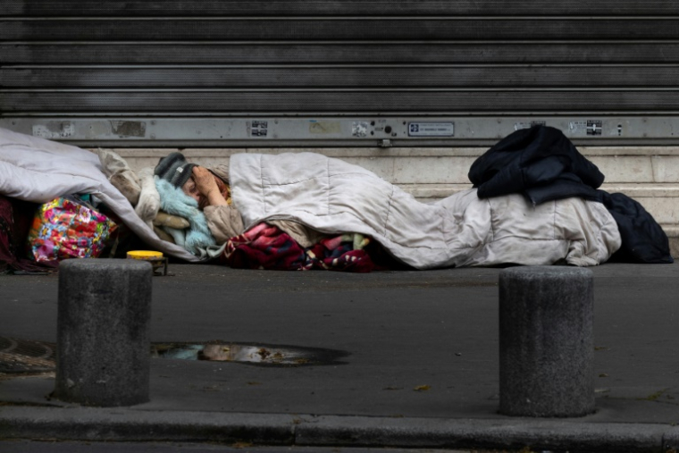 Un sans-abri dort sur un trottoir à Paris, le 21 avril 2025 ( AFP / JOEL SAGET )
