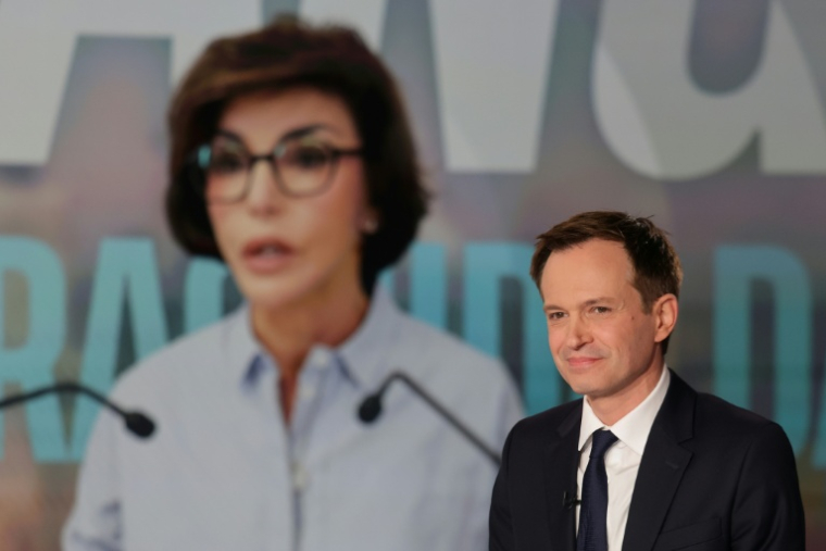 Le candidat Horizons/Renaissance aux municipales Pierre-Yves Bournazel sur le plateau du JT de France 2 à Paris, le 16 mars 2026, devant une photo de la candidate LR/centre Rachida Dati ( AFP / Ludovic MARIN )