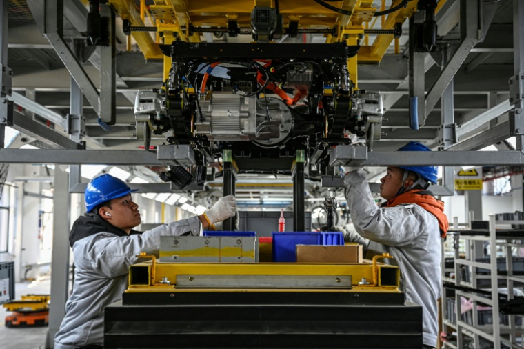 Des ouvriers travaillent sur une ligne de production de l'usine Neolix qui fabrique de petits véhicules utilitaires autonomes pour le transport de colis en ville, le 4 décembre 2025 à Yancheng dans la province chinoise du Jiangsu  ( AFP / Jade GAO )