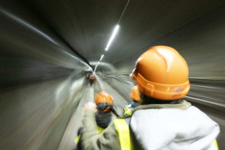 Des membres du personnel circulent en scooter électrique dans le tunnel du BedrettoLab, un centre de recherche souterrain unique, dans un tunnel de 5,2 km près de Bedretto, le 29 avril 2026 en Suisse ( AFP / Ennio LEANZA )