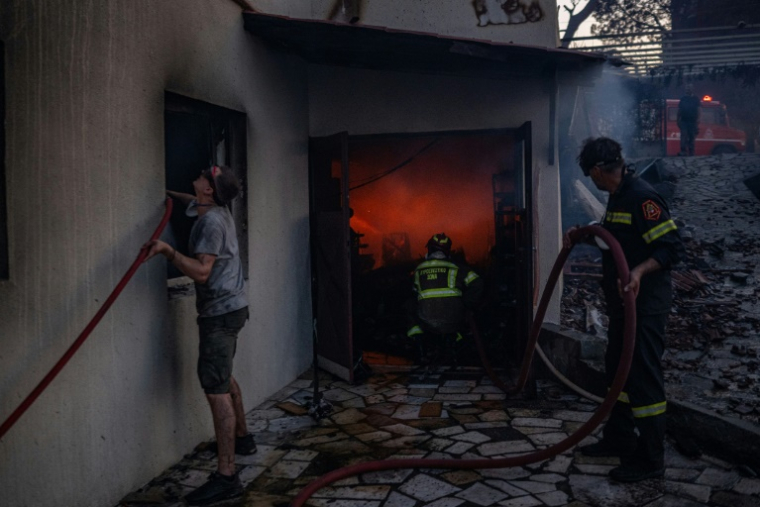 Des habitants et des pompiers luttent contre les flammes à Kryoneri, près d'Athènes, le 26 juillet 2025 ( AFP / Angelos TZORTZINIS )