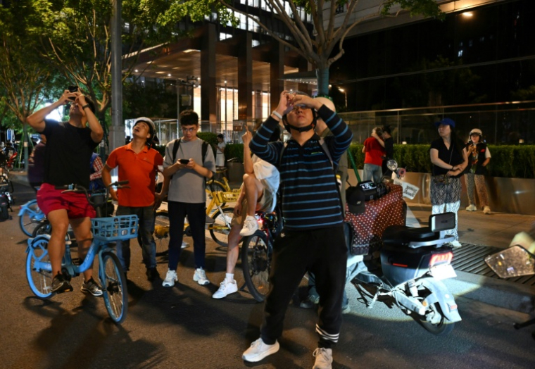 Des personnes photographient la tour CITIC à Pékin, après que des témoins ont signalé la présence de débris d'avion au pied du plus haut bâtiment de la ville, le 26 juin 2026 en Chine ( AFP / Adek BERRY )