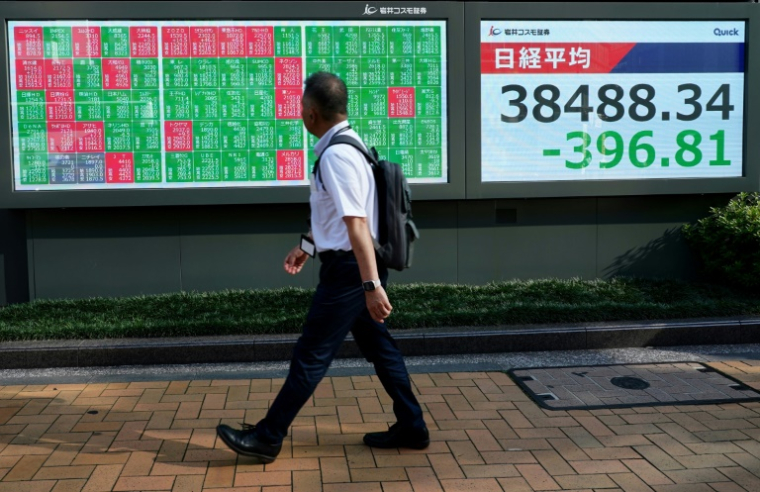 Un piéton passe devant des tableaux d'indices boursiers, le 19 juin 2025 à Tokyo ( AFP / Kazuhiro NOGI )