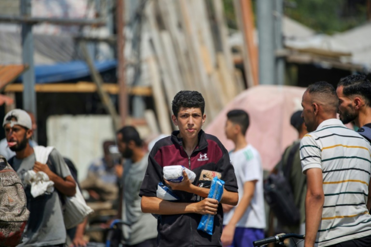 Des déplacés palestiniens portent des produits alimentaires obtenus à un point de distribution du centre de la bande de Gaza, le 26 juillet 2025 ( AFP / Eyad BABA )