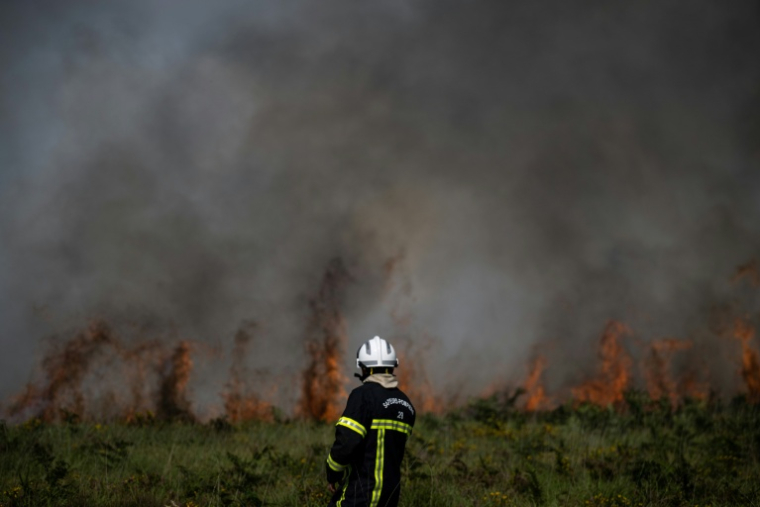 Un sapeur pompier lutte contre un incendie touchant les Monts d'Arrée, près de Brasparts (Finistère), le 19 juillet 2022 ( AFP / LOIC VENANCE )