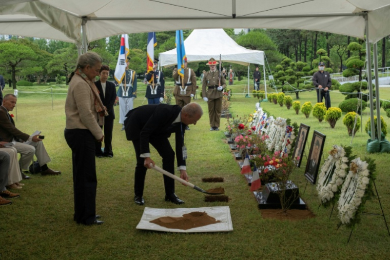 Elisabeth Magrou watches her brother Christophe Grisolet throw a shovelful of earth on the grave of their father Jacques Grisolet, French veteran of the Korean War, at the United Nations memorial cemetery in Busan, on May 27, 2026 in South Korea ( AFP / Roland DE COURSON)