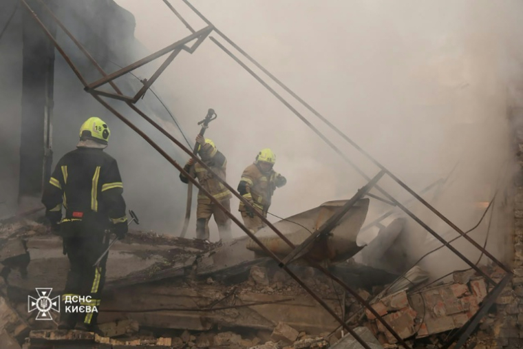 Photo diffusée par le Service d'État ukrainien pour les situations d'urgence, le 11 juillet 2026, montrant des pompiers luttant contre un incendie dans un entrepôt endommagé par une frappe de missiles russes à Kiev, en Ukraine ( Service d'État ukrainien pour les situations / Handout )