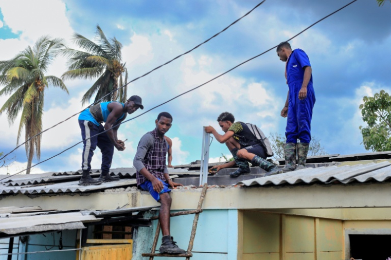 Les habitants réparent le toit d'une maison détruite trois semaines plus tôt par l'ouragan Melissa à El Cobre, le 17 novembre 2025 à Cuba ( AFP / STRINGER )
