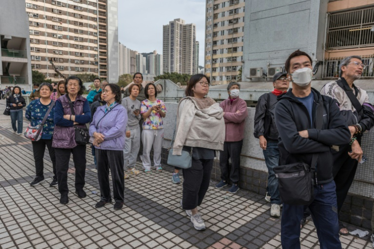 Des habitants observent des appartements encore en flammes après un violent incendie qui a ravagé plusieurs immeubles du complexe résidentiel Wang Fuk Court à Hong Kong, le 27 novembre 2025  ( AFP / Dale DE LA REY )