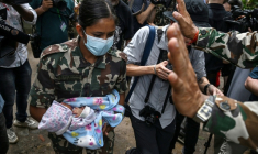 Une militaire porte un bébé secouru après la crue destructrice qui a fait au moins 633 morts à la frontière entre le Népal et la Chine, le 29 août 2026 au camp de Trishuli, au nord de Katmandou  ( AFP / Arun SANKAR )