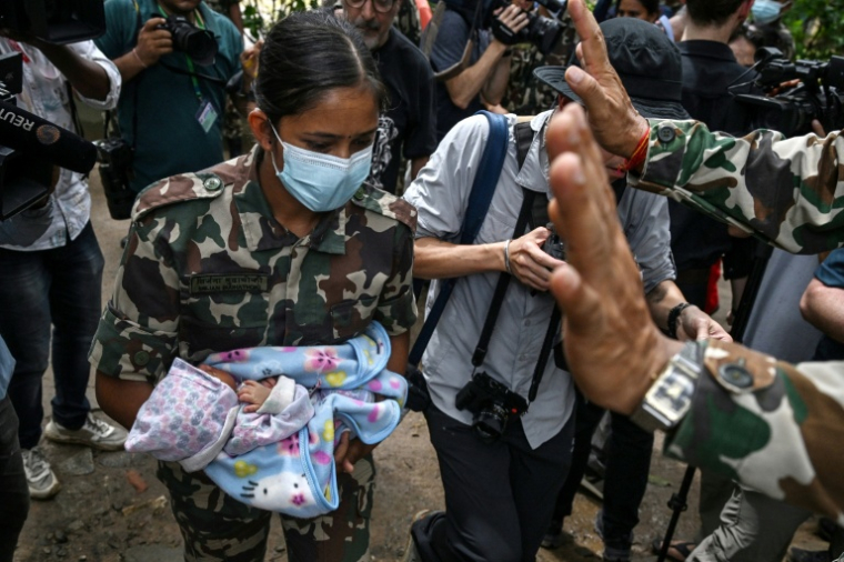Une militaire porte un enfant secouru après la crue destructrice qui a fait au moins 633 morts à la frontière entre le Népal et la Chine, le 29 août 2026 au camp de Trishuli, dans le district népalais de Nuwakot   ( AFP / Arun SANKAR )