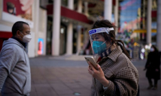 Une femme portant un masque de protection et un écran facial marche à Shanghai, en Chine