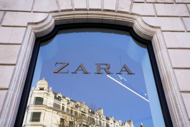 Un bâtiment se reflète dans la vitrine d'un magasin de vêtements Zara à Bilbao
