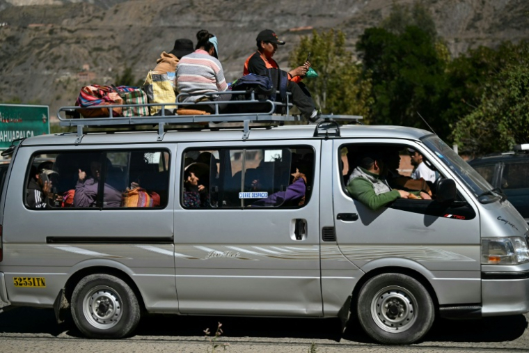 Des personnes voyagent sur le toit d'un minivan chargé après la réouverture d'une route, auparavant bloquée par des  manifestations réclamant la démission du président bolivien Rodrigo Paz à Carreras, dans le département de La Paz, en Bolivie, le 5 juin 2026 ( AFP / MARVIN RECINOS )