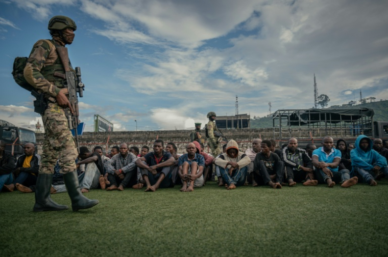 Un soldat du M23 surveille des combattants "neutralisés" du FDLR et d'autres groupes armés dans un stade de Goma, en République démocratique du Congo, le 10 mai 2025 ( AFP / Jospin Mwisha )