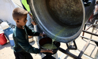 Un garçon palestinien reçoit les dernières gouttes d'une soupe aux lentilles à un point de distribution de nourriture dans la ville de Gaza, le 1er août 2025 ( AFP / Omar AL-QATTAA )