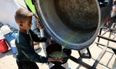 Un garçon palestinien reçoit les dernières gouttes d'une soupe aux lentilles à un point de distribution de nourriture dans la ville de Gaza, le 1er août 2025 ( AFP / Omar AL-QATTAA )