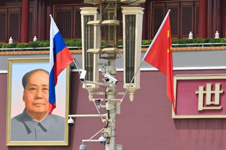 Le drapeau national russe (g) flotte à côté du drapeau chinois près d'un portrait du défunt dirigeant communiste Mao Tsé-toung devant la porte de Tiananmen, lors de la visite d'Etat du président russe Vladimir Poutine à Pékin, le 16 mai 2024 ( AFP / HECTOR RETAMAL )