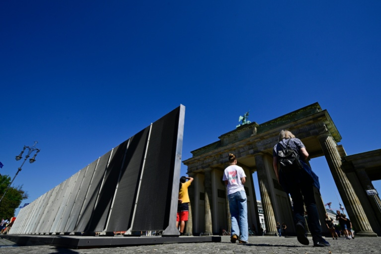 Des personnes regardent la Porte de Brandebourg lors d'une cérémonie commémorant le 65e anniversaire de l'édification du Mur de Berlin, à Berlin, le 13 août 2026 ( AFP / John MACDOUGALL )
