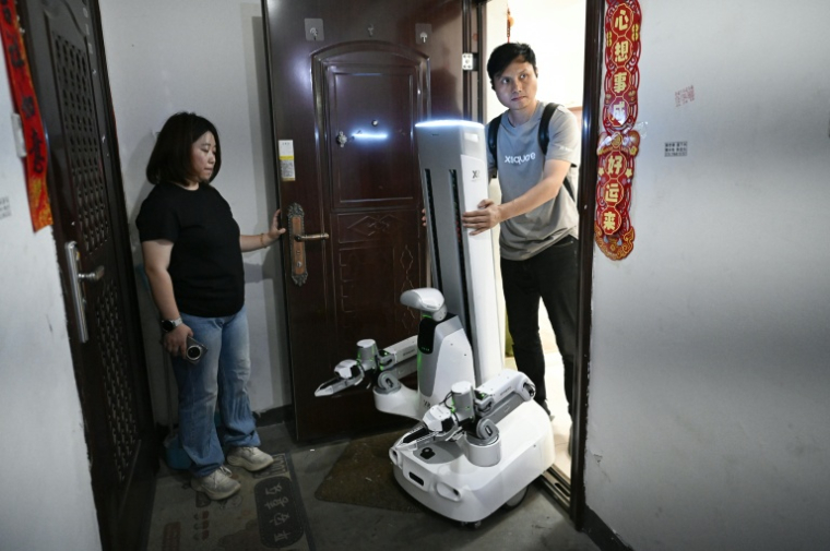 Un ingénieur de X Square emmène un robot après qu'il a effectué des tâches ménagères au domicile d'une cliente , le 21 mai 2026 à Pékin, en Chine ( AFP / WANG Zhao )