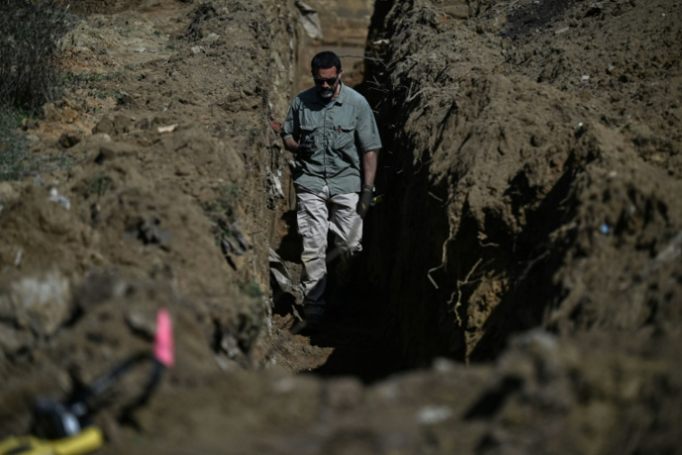 Un expert médicolégal inspecte un trou fraîchement creusé lors de fouilles menées dans le cadre des recherches de personnes disparues de la guerre du Kosovo, près de la ville de Rahovec, le 11 mars 2026 ( AFP / Armend NIMANI )