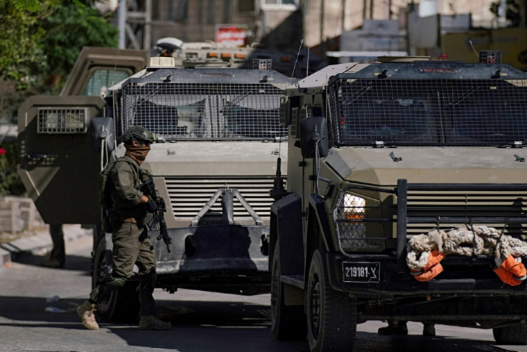 Des soldats israéliens à côté de véhicules blindés lors d'un raid militaire à Jénine, le 21 mai 2025 en Cisjordanie occupée ( AFP / Mohammad MANSOUR )