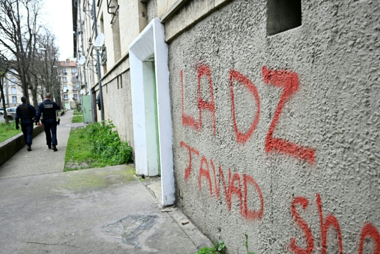 Des policiers patrouillent à proximité d'un mur avec un tag DZ désignant la DZ mafia à Avignon le 13 mars 2025 ( AFP / GABRIEL BOUYS )