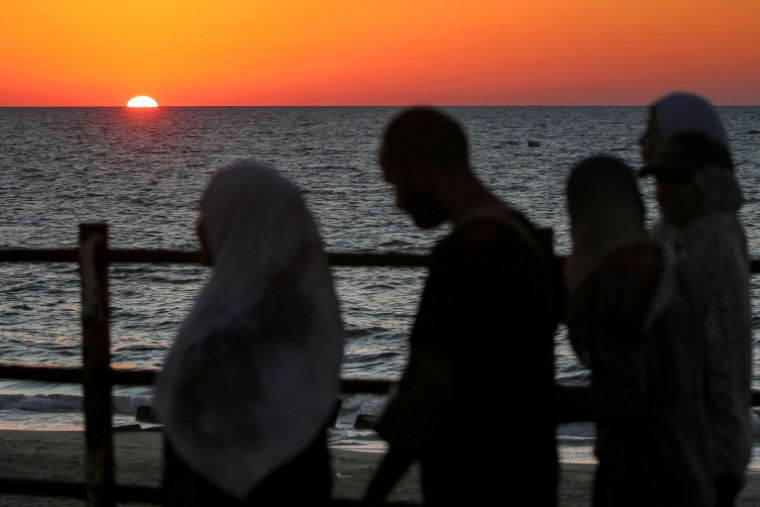 Le soleil se couche sur la mer Méditerranée alors que des Palestiniens déplacés évacuent la ville de Gaza vers le sud de la bande de Gaza face aux bombardements israéliens, le 13 septembre 2025 dans la bande de Gaza ( AFP / Eyad BABA )