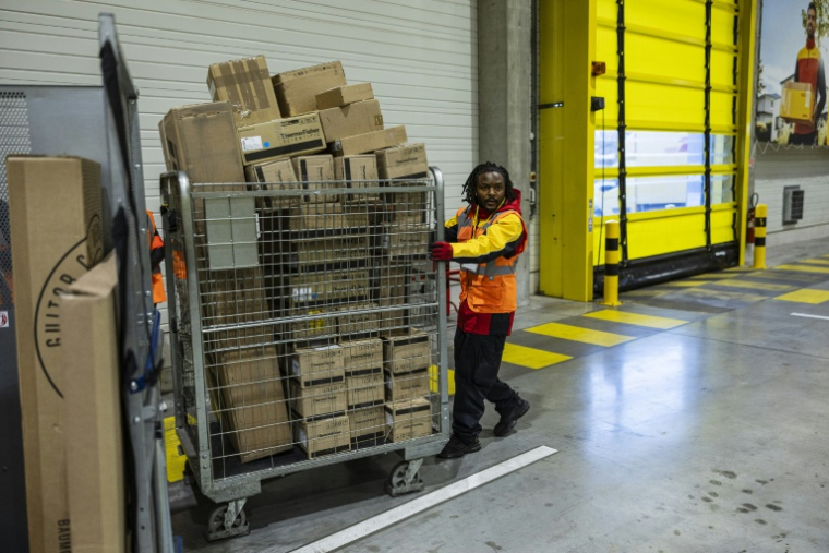 Un employé pousse un conteneur de colis dans un entrepôt DHL à Lesquin, près de Lille, le 12 novembre 2025 ( AFP / Sameer Al-DOUMY )