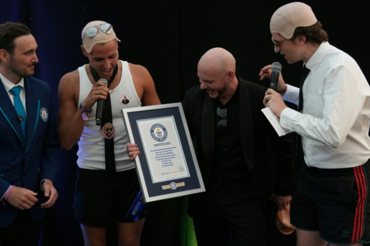 Le rappeur américain Pitbull (2eD) reçoit son diplôme du Guinness des records grâce à un rassemblement de 22.141 fans portant de faux crânes chauves, le 10 juillet 2026 à Londres ( AFP / CARLOS JASSO )