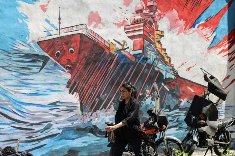 Une femme passe devant une fresque anti-américaine et anti-israélienne à Téhéran, le 10 mai 2026. ( AFP / ATTA KENARE )