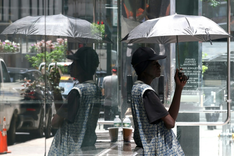 Un homme se protège du soleil avec un parapluie dans le centre de Manhattan, le 23 juin 2025 à New York, alors qu'une alerte à la chaleur extrême a été émise pour la région ( AFP / TIMOTHY A. CLARY )