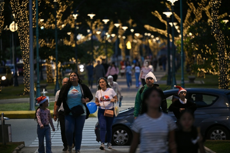 Des passants sous des décorations de Noël à Caracas, le 19 décembre 2025 au Venezuela ( AFP / Federico PARRA )
