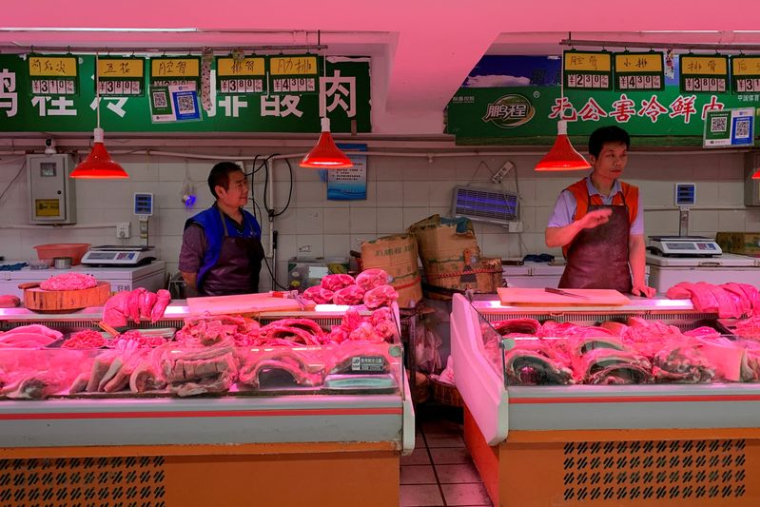 PHOTO DE FICHIER : Des vendeurs de porc tiennent leurs étals sur un marché de Pékin