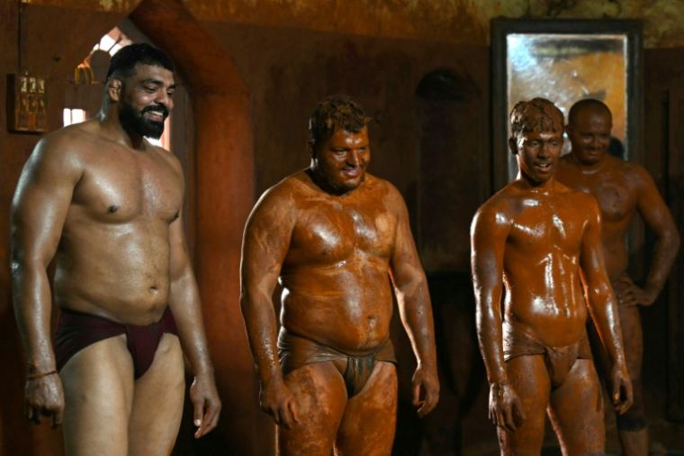 Le lutteur profesionnel Mauli Jamdade (g), aux côtés d'autres lutteurs, regarde un entraînement de juniors dans un gymnase à Kolhapur, dans l'État du Maharashtra, le 30 avril 2025 en Inde ( AFP / Indranil MUKHERJEE )
