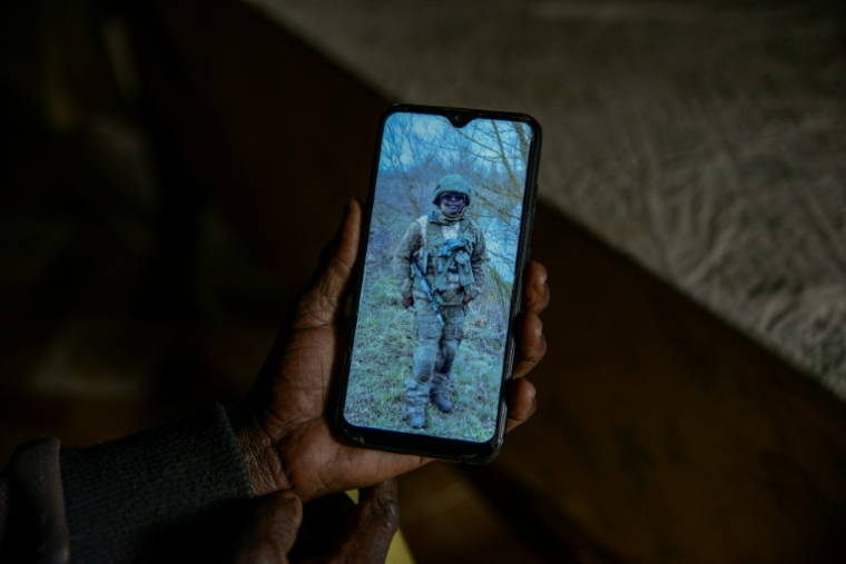 Josephine Ngoya, la mère d'Erastus Mundia, montre une photo de son fils, chez elle à Nabemo au Kenya, le 27 février 2026 ( AFP / Brian ONGORO )
