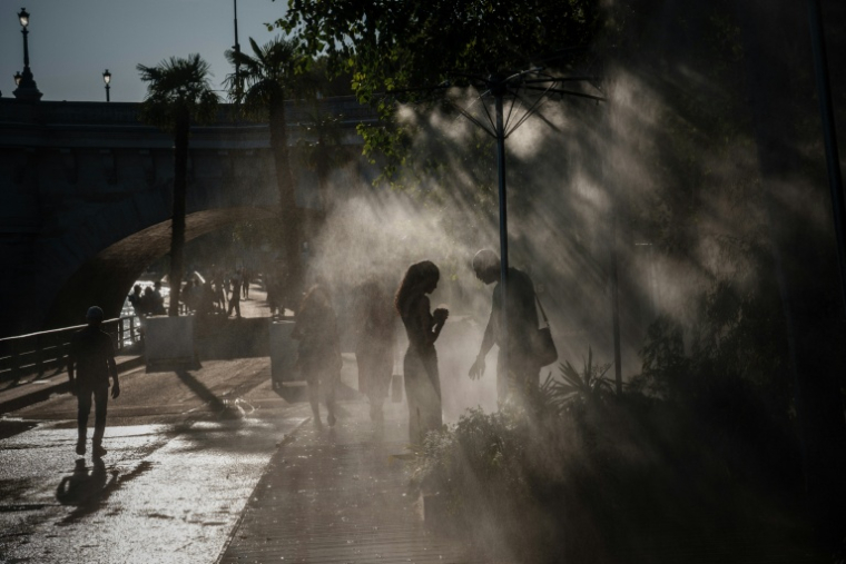 Des personnes se rafraîchissent sous des brumisateurs à Paris, le 10 juillet 2026 ( AFP / DIMITAR DILKOFF )