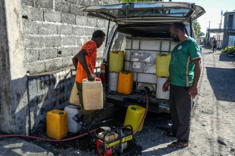 des habitants repartent avec des bidons remplis d'eau potable à la pompe du quartier, à Moroni, aux Comores, le 18 juillet 2026 ( AFP / Ibrahim YOUSSOUF )