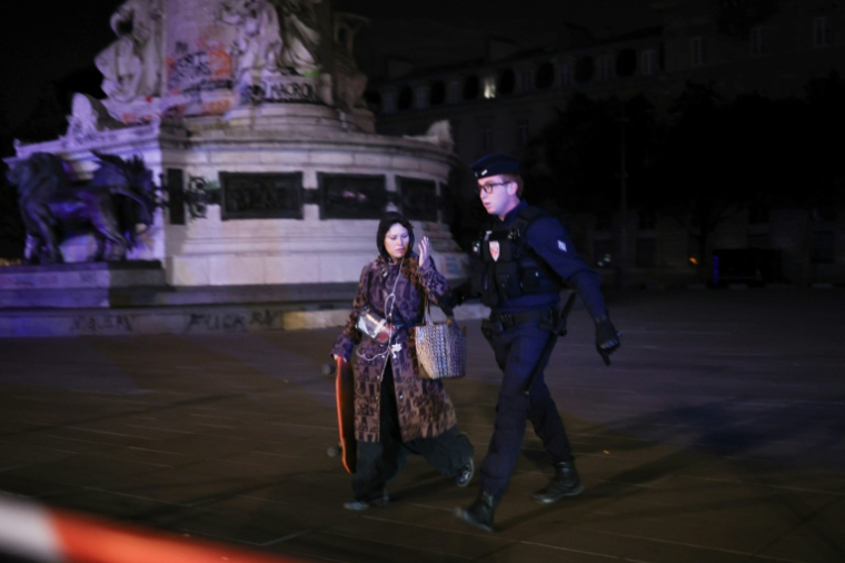 Un policier accompagne une skateuse hors de la place de la République, lors d’un couvre-feu partiel à Paris, aux premières heures du 21 octobre 2026 ( AFP / SIMON WOHLFAHRT )