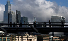 Des personnes marchent près du Millenium Bridge avec le quartier financier de la City de Londres derrière