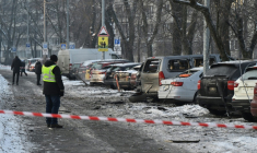 Des habitants devant des voitures endommagées sur un site où des débris de drones russes sont tombés durant une attaque arérienne massive russe, à Kiev en Ukraine le 20 janvier 2026 ( AFP / Genya SAVILOV )