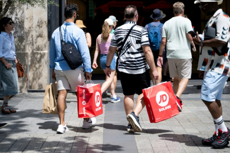 Des passants portent des sacs de courses à Paris, le 25 juin 2025, premier jour des soldes d'été en France ( AFP / Emma DA SILVA )