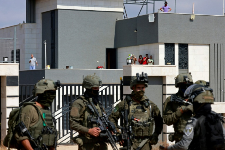 Des soldats israéliens devant l'entrée d'une maison palestinienne assiégée par des colons israéliens dans le village de Qusra, au sud de Naplouse, en Cisjordanie occupée, le 14 août 2026 ( AFP / Jaafar ASHTIYEH )